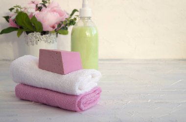 Sıvı sabun ve beyaz zemin üzerine iki havlu.