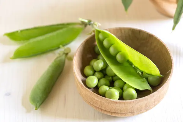 Guisantes verdes jóvenes sobre fondo de madera blanca . — Foto de Stock