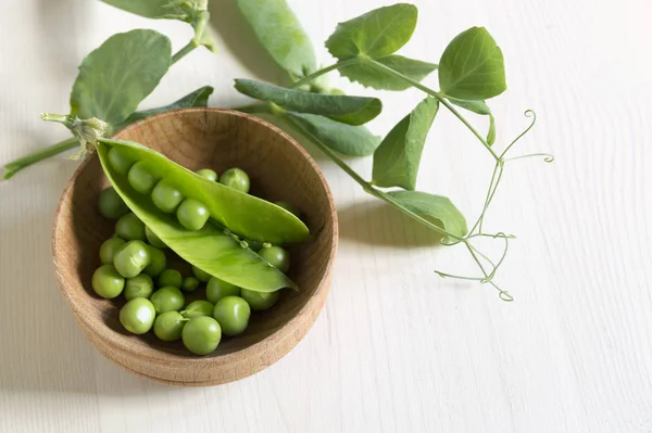 Guisantes verdes jóvenes sobre fondo de madera blanca . — Foto de Stock