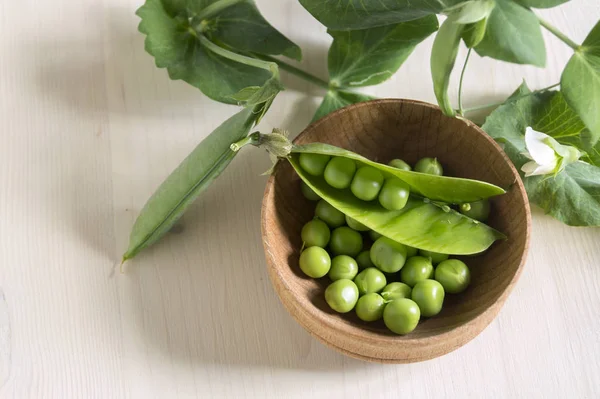 Guisantes verdes jóvenes sobre fondo de madera blanca . — Foto de Stock