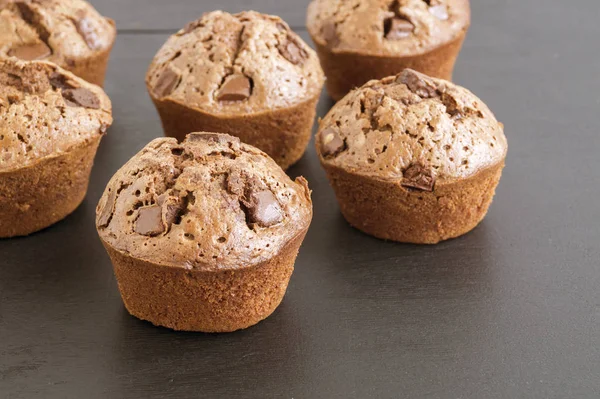 Cupcakes de chocolate com pedaços de chocolate em um fundo preto . — Fotografia de Stock