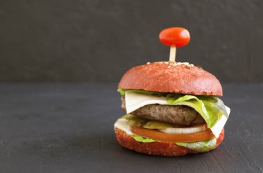 Siyah arka planda renkli çöreklerle hamburgerler.