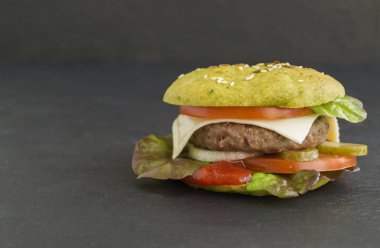 Siyah arka planda renkli çöreklerle hamburgerler.