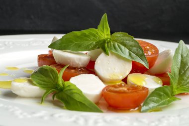 Olgun domatesli Caprese salatası ve taze fesleğen yapraklı mozzarella. İtalyan yemeği..