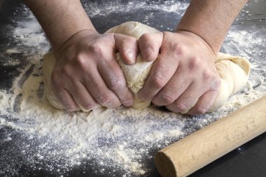 Erkek eli un kaplı bir masada hamur yoğurur..