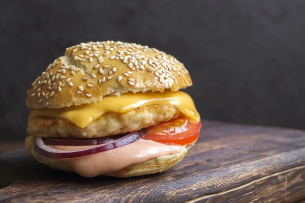 fish Burger with sauce and cheese on a wooden table.