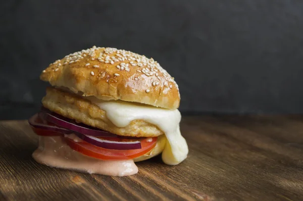 fish Burger with sauce and cheese on a wooden table.