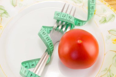 Ölçüm bandı ve bir çatal ile domates izole 