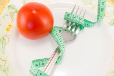 Ölçüm bandı ve bir çatal ile domates izole 