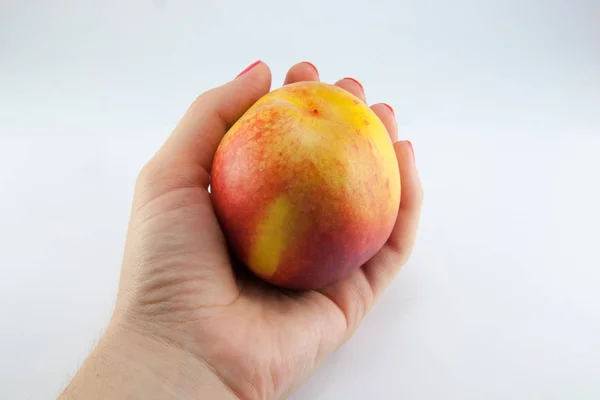 Рука со свежим сочным персиком, разделенным пополам — стоковое фото
