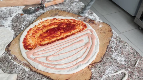 Chef mano está extendiendo pasta de tomate pasteurizado en una pizza bas —  Fotos de Stock