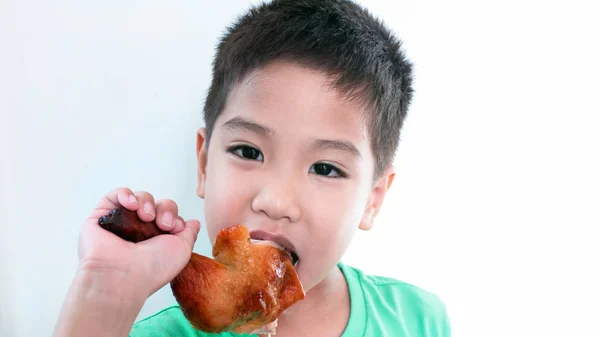 Азиатский мальчик ест жареную куриную ногу — стоковое фото