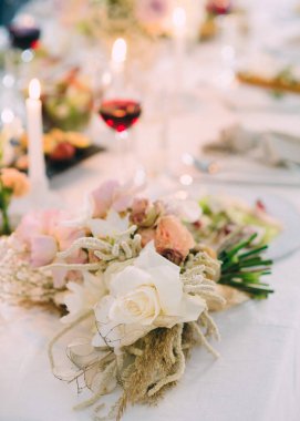 Çiçek buketi, şarap ve mumlarla süslü bir masa.