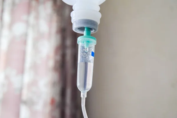 Рука тримає солону IV краплю для пацієнта в лікарняній кімнаті — стокове фото