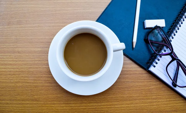 Bürotisch mit Tasse Kaffee auf Holzhintergrund — Stockfoto