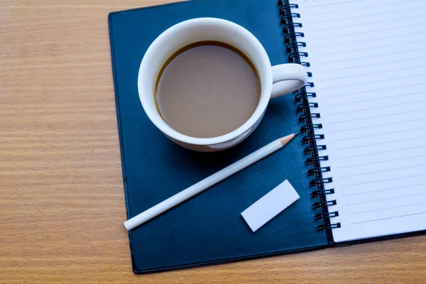 Bürotisch mit Tasse Kaffee auf Holzhintergrund — Stockfoto