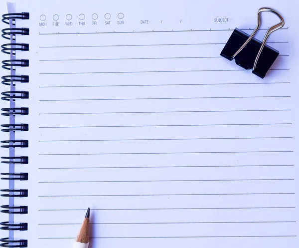 Notizbuch mit weißem Bleistift und schwarzer Büroklammer auf weißem Hintergrund für Textur — Stockfoto