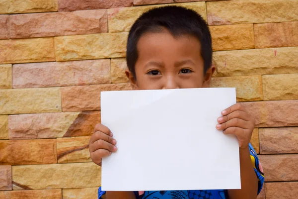 Niño mantenga papel blanco en blanco con fondo de pared de piedra — Foto de Stock