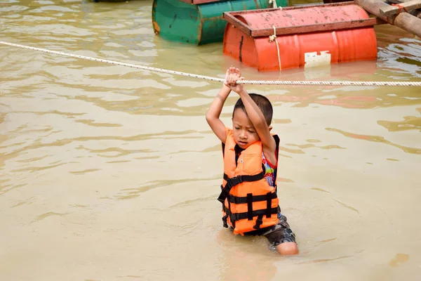 Niño jugando aguas con chaleco salvavidas, concepto de artículos de seguridad del agua — Foto de Stock