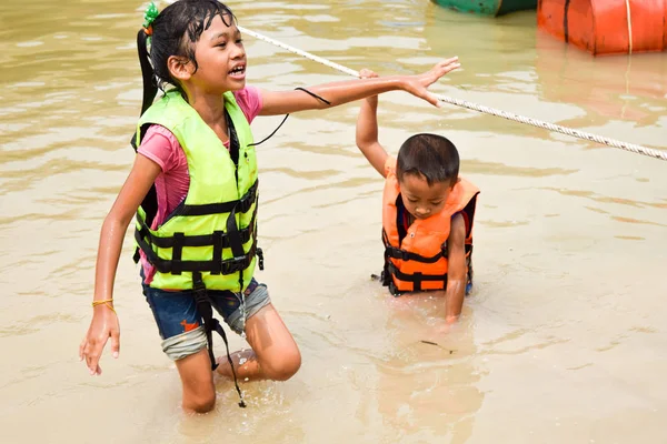 Dos niños con chaleco salvavidas jugando al agua, concepto de artículos de seguridad del agua — Foto de Stock