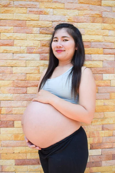 taş duvar arka plan ile güzel bir hamile kadın