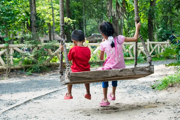 Dos niños sentados en swing, concepto familiar — Foto de Stock