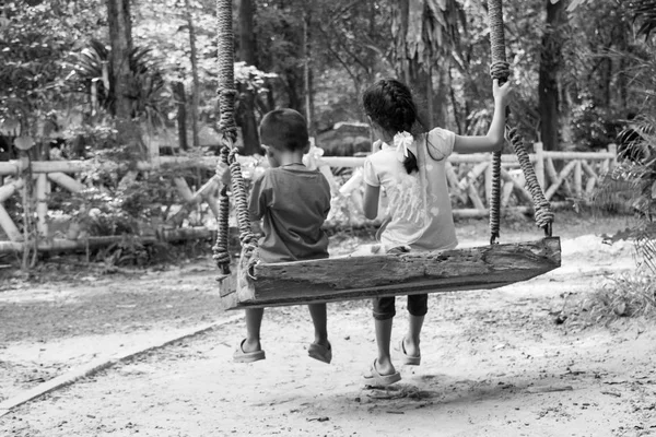 Siyah ve beyaz, aile kavramı oturan iki çocuk salıncak — Stok fotoğraf