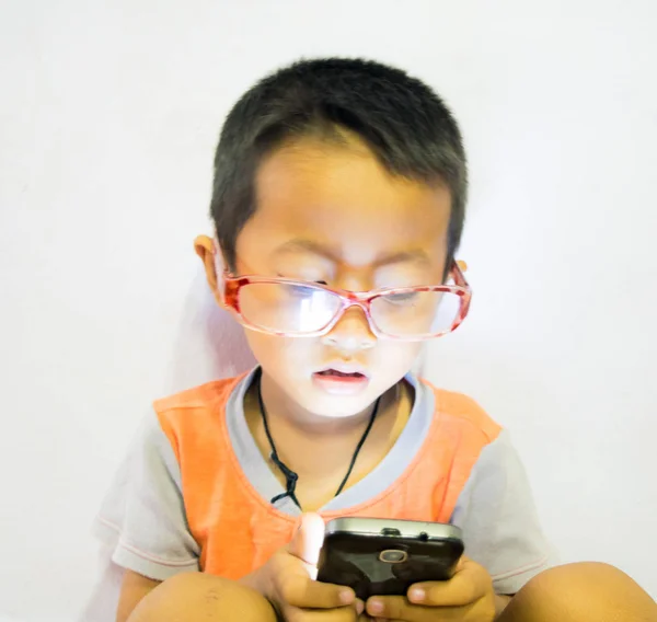 Концентрированный мальчик играет с мобильным телефоном, смартфоном — стоковое фото