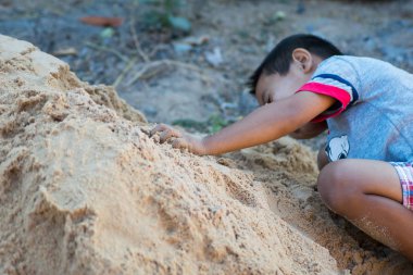 Çocuk kumda oynuyor.