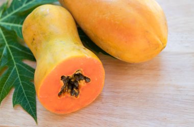 Ahşap zemin üzerine yeşil yaprak ile olgun papaya