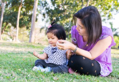 parkta çim bebekle oynamak anne