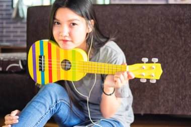 Asyalı genç kadın oynarken ukulele