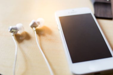 Akıllı telefon ve kulaklık ahşap arka plan üzerinde