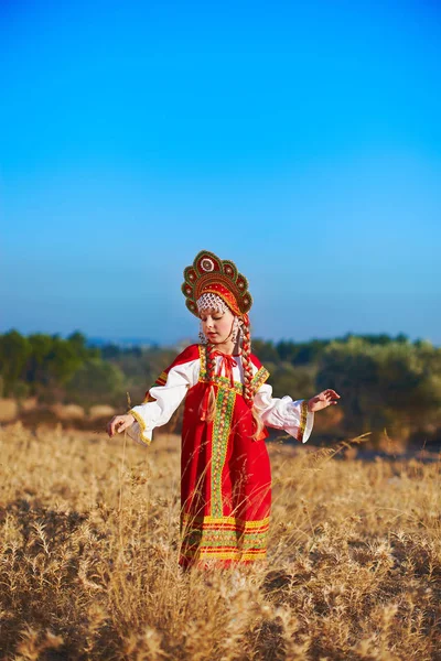 Красивая девушка в русском народном костюме танцует на поле — стоковое фото