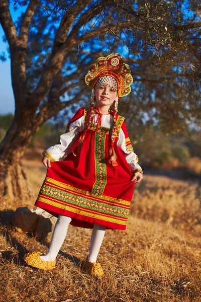 Красивая блондинка в русском народном костюме танцует под деревом — стоковое фото