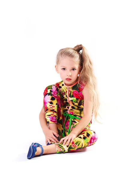 Linda loira seis anos de idade menina pequena em macacão colorido no fundo branco sentado — Fotografia de Stock