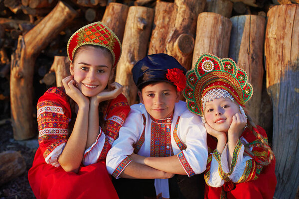Three Russian kids in russian folk costume boy and girl playing together and emotionally smiling