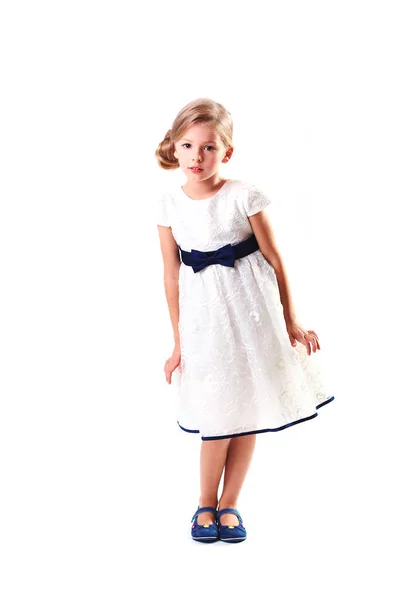 Bastante rubia niña de seis años de edad sobre fondo blanco en vestido de fiesta blanco de altura completa — Foto de Stock