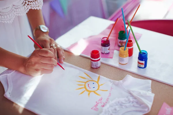 Mom painting baby cloth for her baby girl.