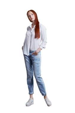 Beyaz gömlek ve mavi kot pantolon giyen Kızıl saçlı güzel genç sıska modeli