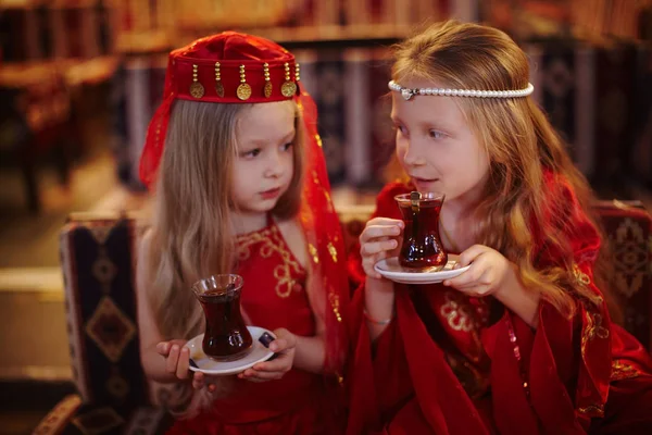 Две девушки в народных арабских костюмах пьют вместе турецкий чай. — стоковое фото