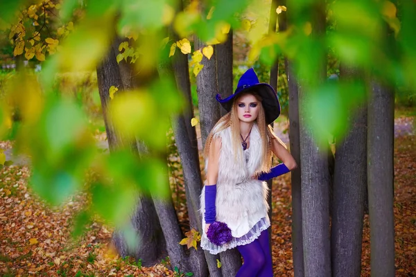 Boda en concepto de Halloween, novia en vestido corto y sombrero de bruja en el parque de otoño . — Foto de Stock