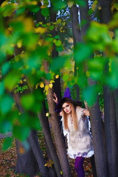 Boda en concepto de Halloween, novia en vestido corto y sombrero de bruja en el parque de otoño . — Foto de Stock