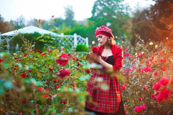 Hermosa chica en traje tradicional popular escocés en el jardín de rosas de flor roja — Foto de Stock