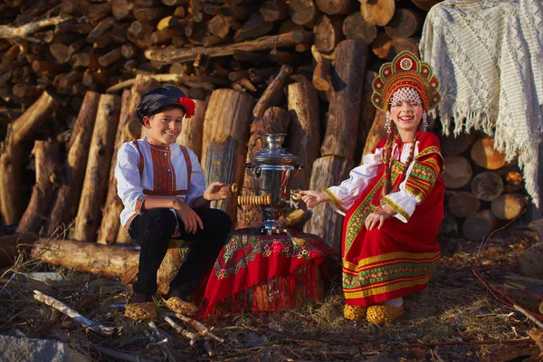 Sister and brother in Russian folk costumes sitting near samovar and laughing — Stock Photo, Image