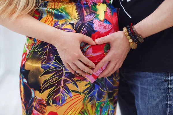 Pregnant couple making heart gesture on belly — Stock Photo, Image