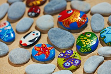 Rounded colorful stones pebbles shingle with pictures painted on them clipart