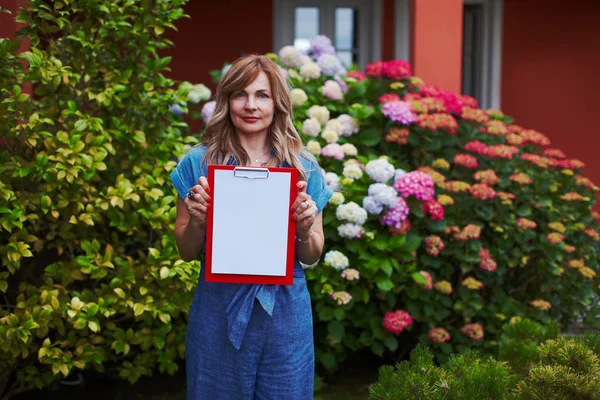 Woman with clipboard at blooming garden working and planning sch — Stock Photo, Image