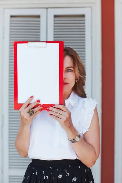 Middle age beautiful woman closing face with empty clipboard wit — Stock Photo, Image