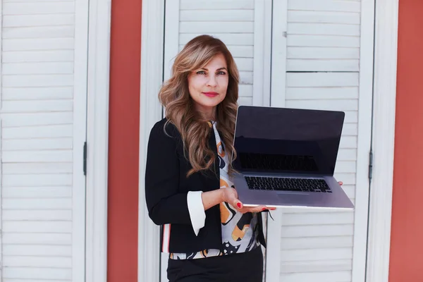 Жінка в діловому костюмі з ноутбуком в руках — стокове фото